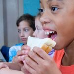 Elementary school students eat peanut putter and jelly sandwiches