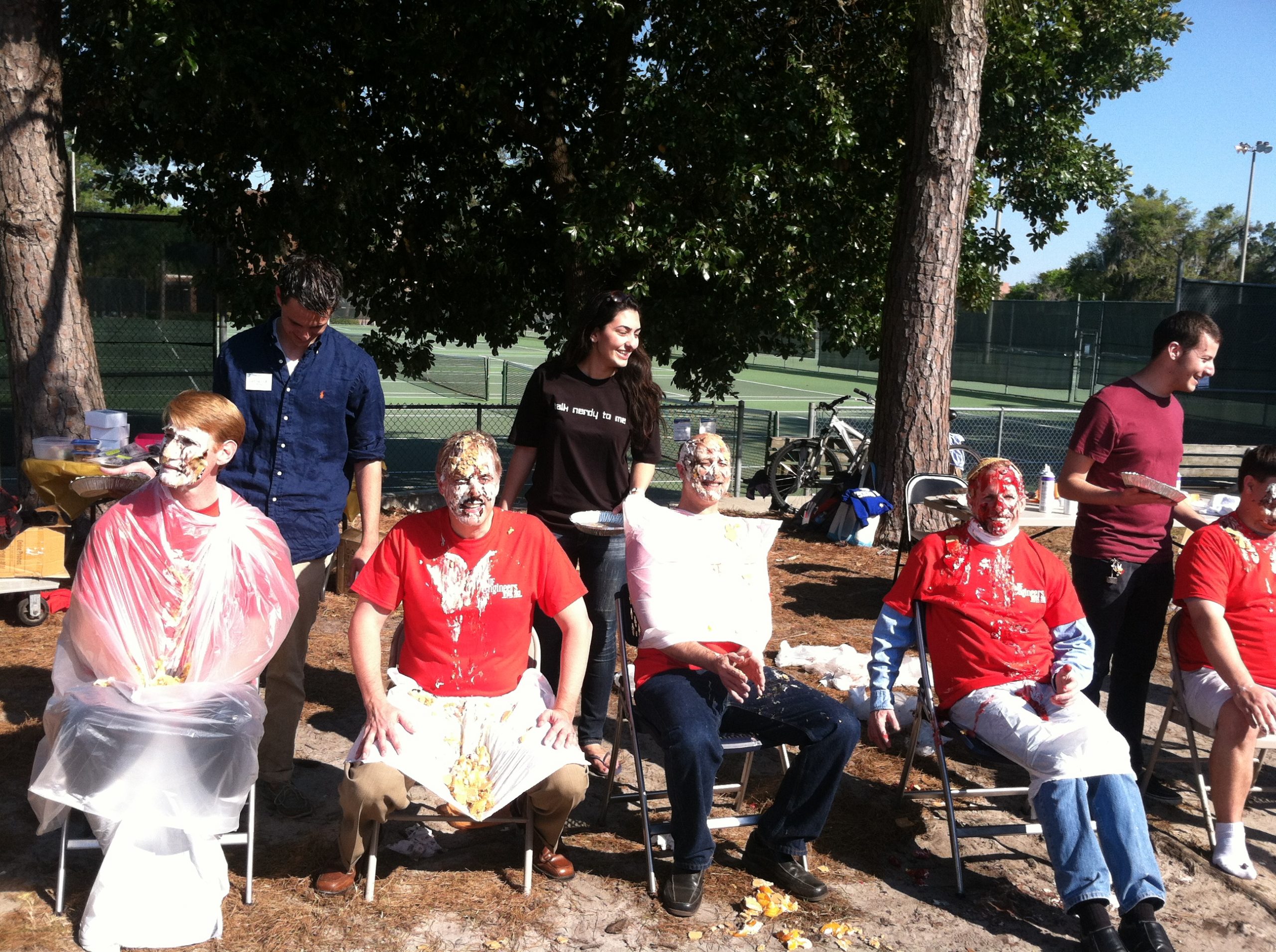 A group of faculty take a seat after being pied in the face